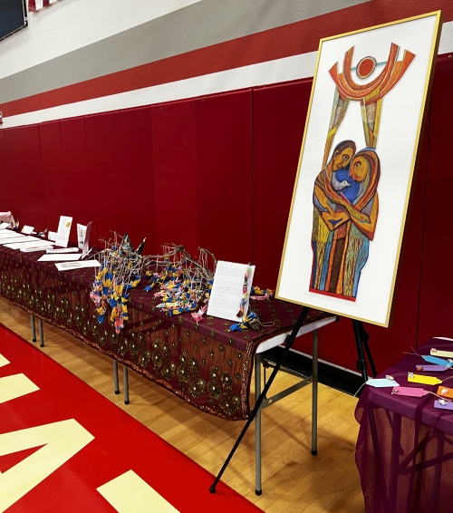 A large painting stands between tables with welcoming and introductory material inside the school